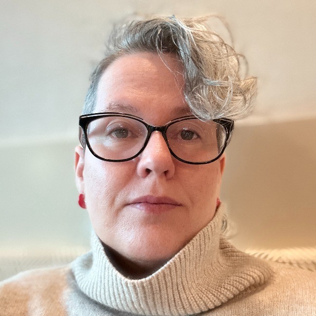 Headshot of Stephanie Roach. Woman with short blonde hair and glasses.